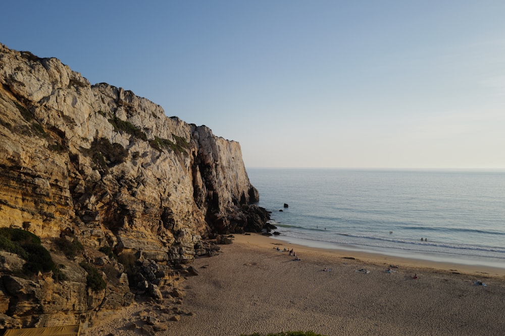 a rocky cliff next to the ocean on a sunny day