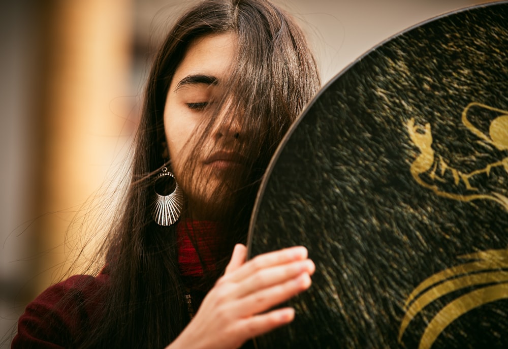 a woman with long hair holding a round object