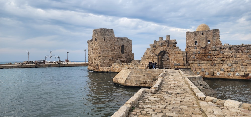 a stone walkway leading to a castle by the water