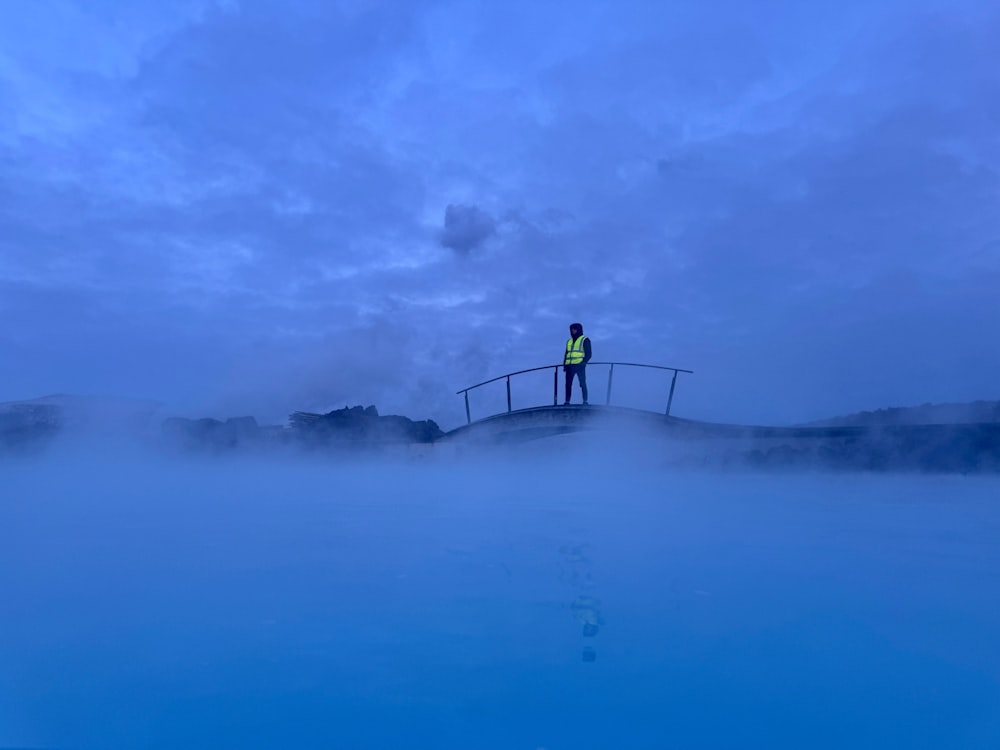 a man standing on a bridge over a body of water