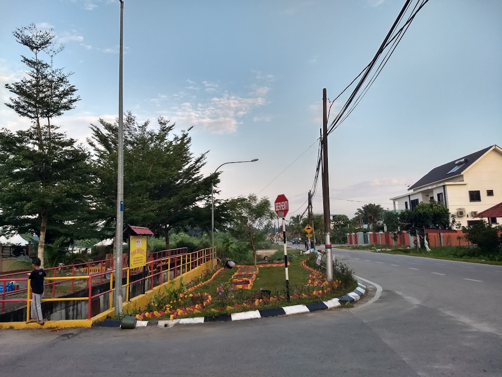 a street with a fence and flowers on the side of the road