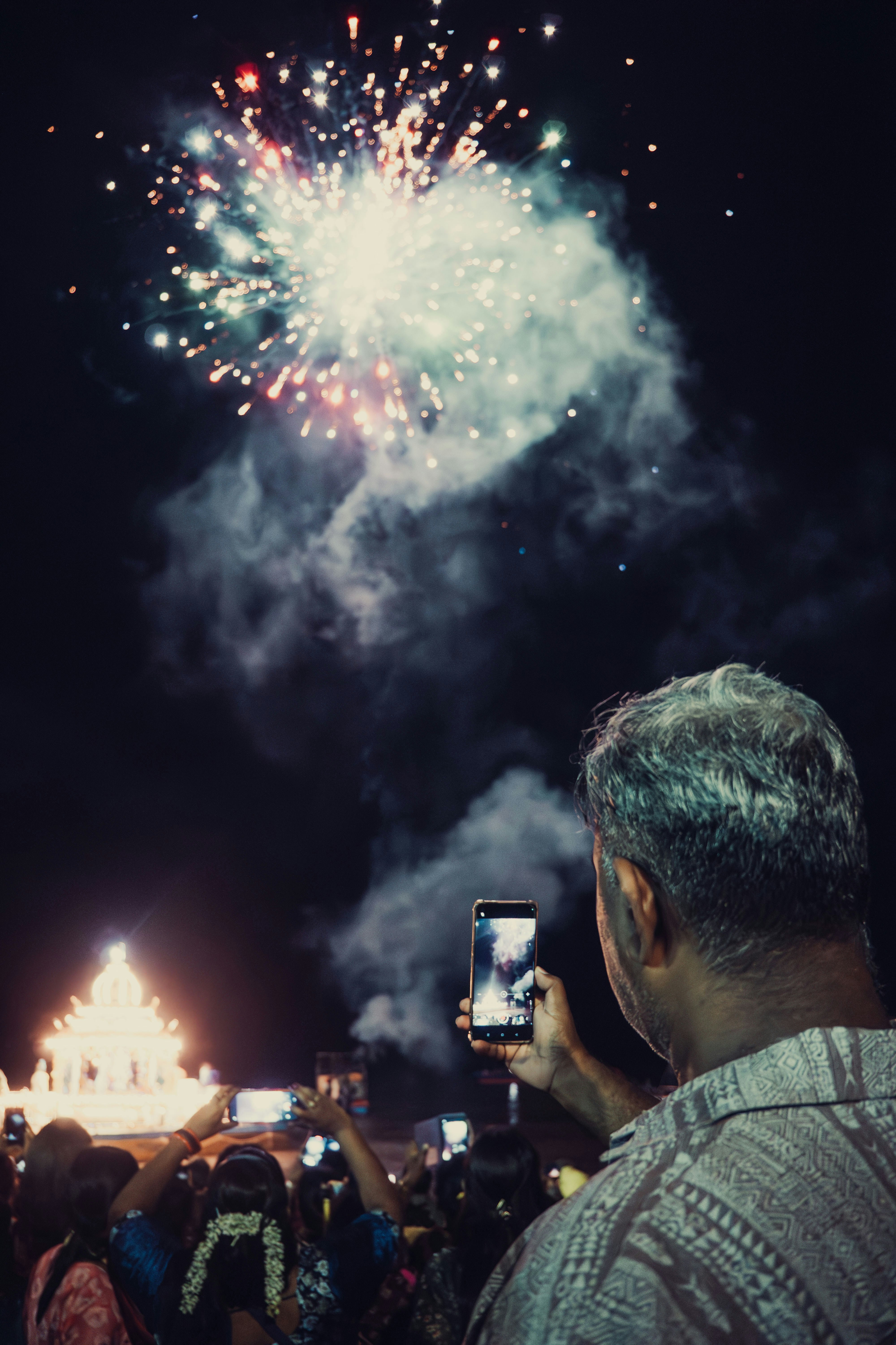 A man taking a picture of a fireworks display