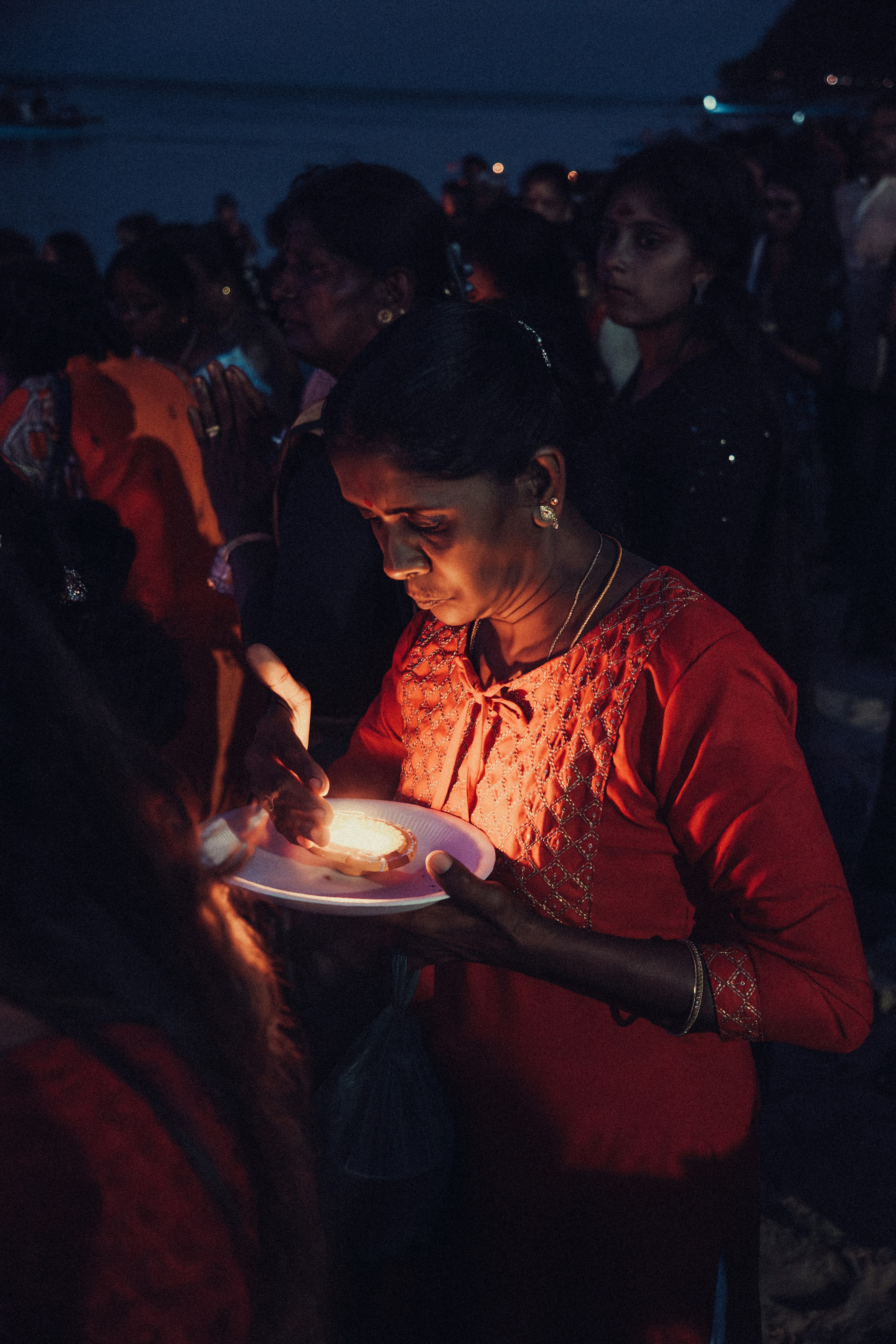 A woman holding a plate of food in front of a crowd