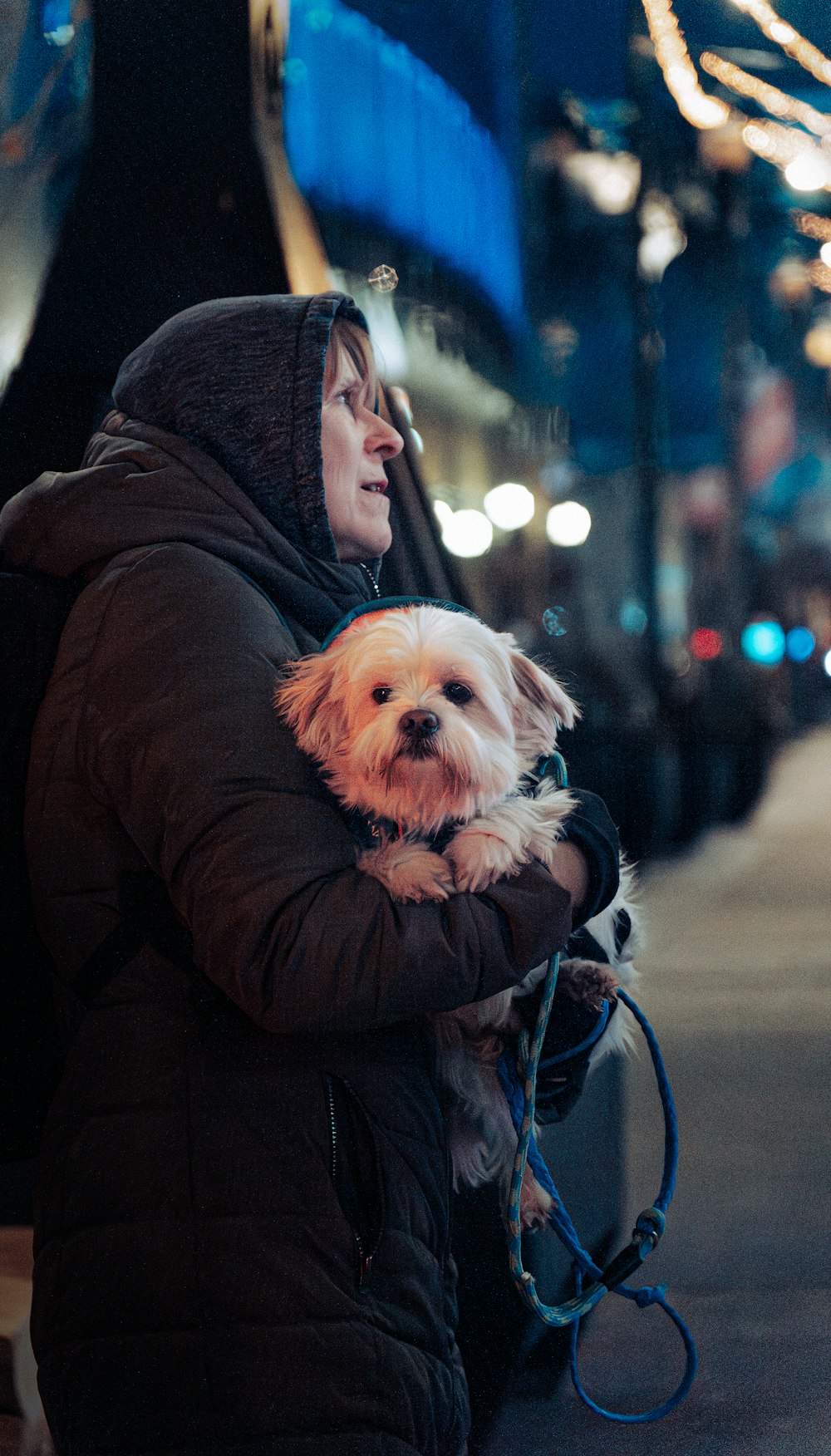 a woman holding a small white dog on a leash