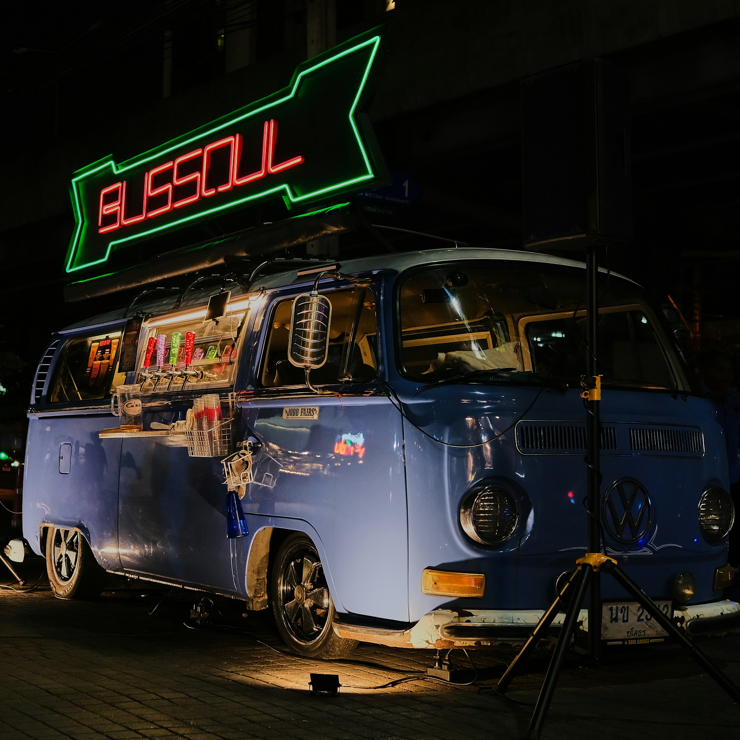 a vw bus parked in front of a neon sign