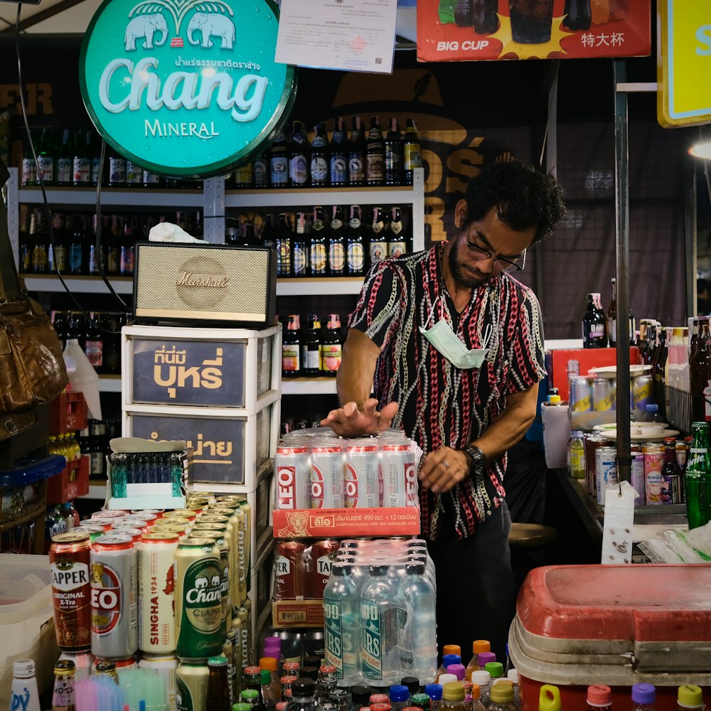 a man standing in front of a store filled with bottles