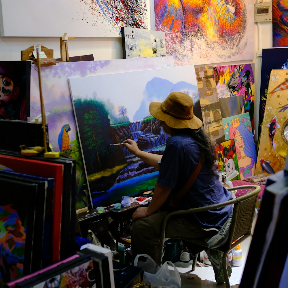 a man sitting in a chair in front of a painting