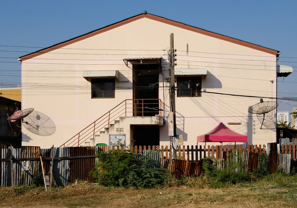 a white building with a red umbrella and a pink tent