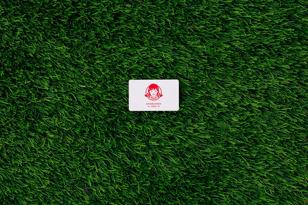 a white square sticker sitting on top of a lush green field
