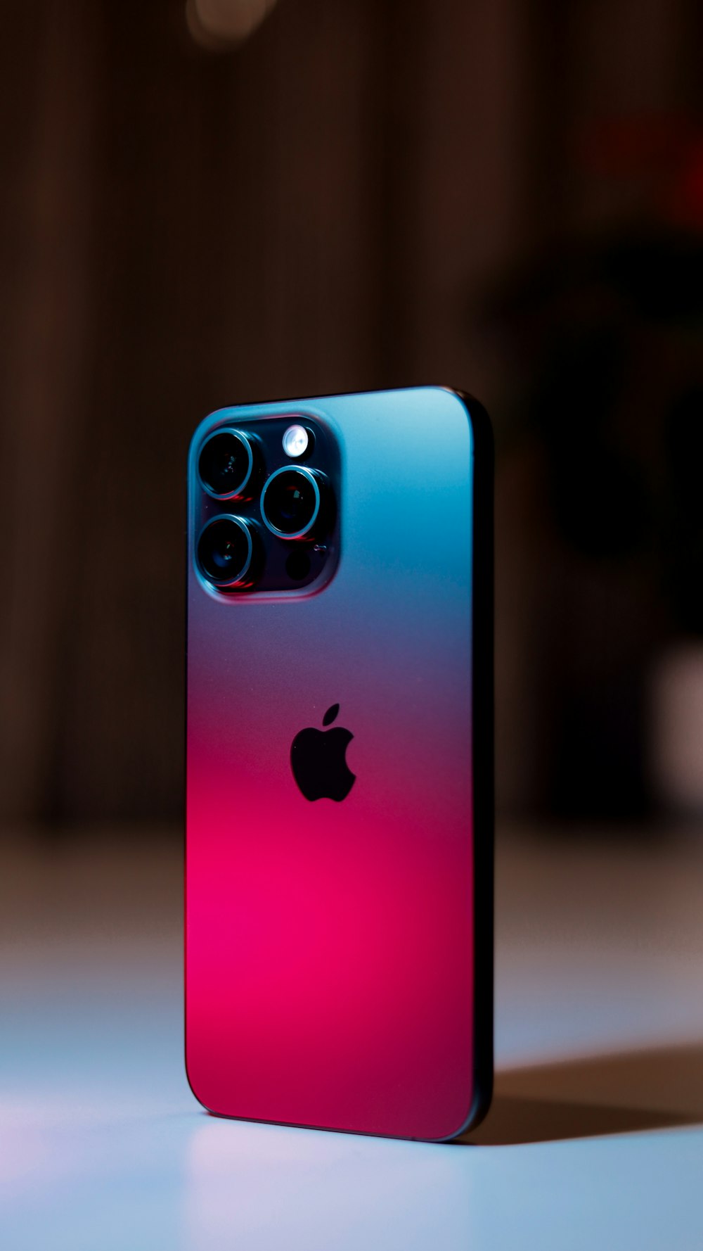Un iPhone rosa e blu seduto sopra un tavolo