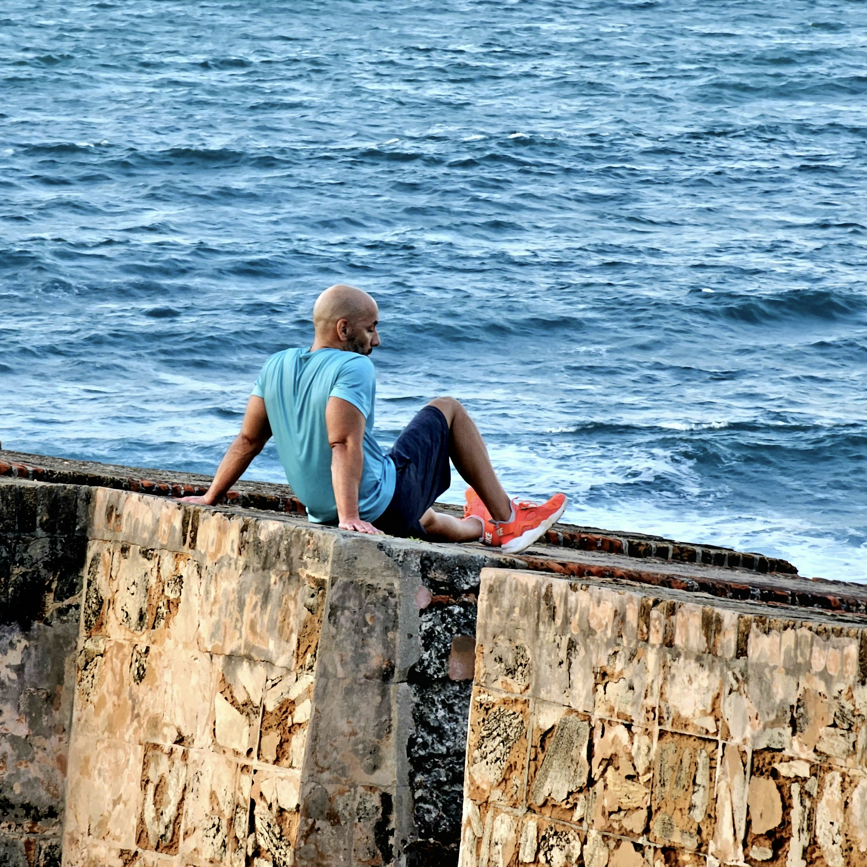 a man sitting on a wall next to the ocean
