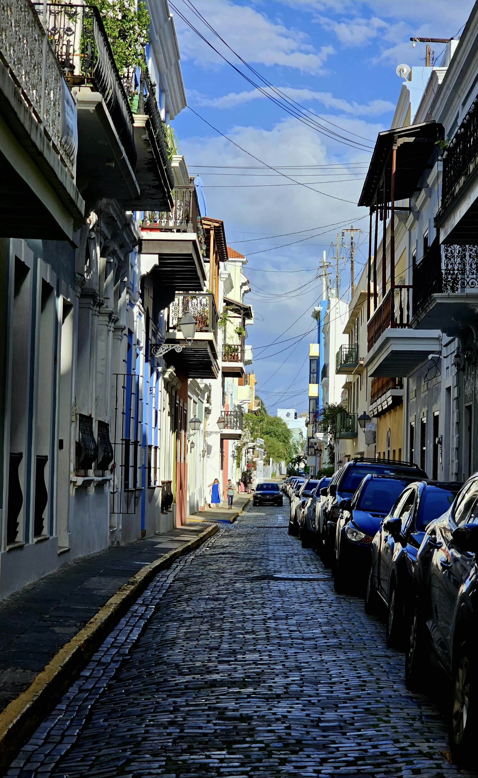 a cobblestone street lined with parked cars