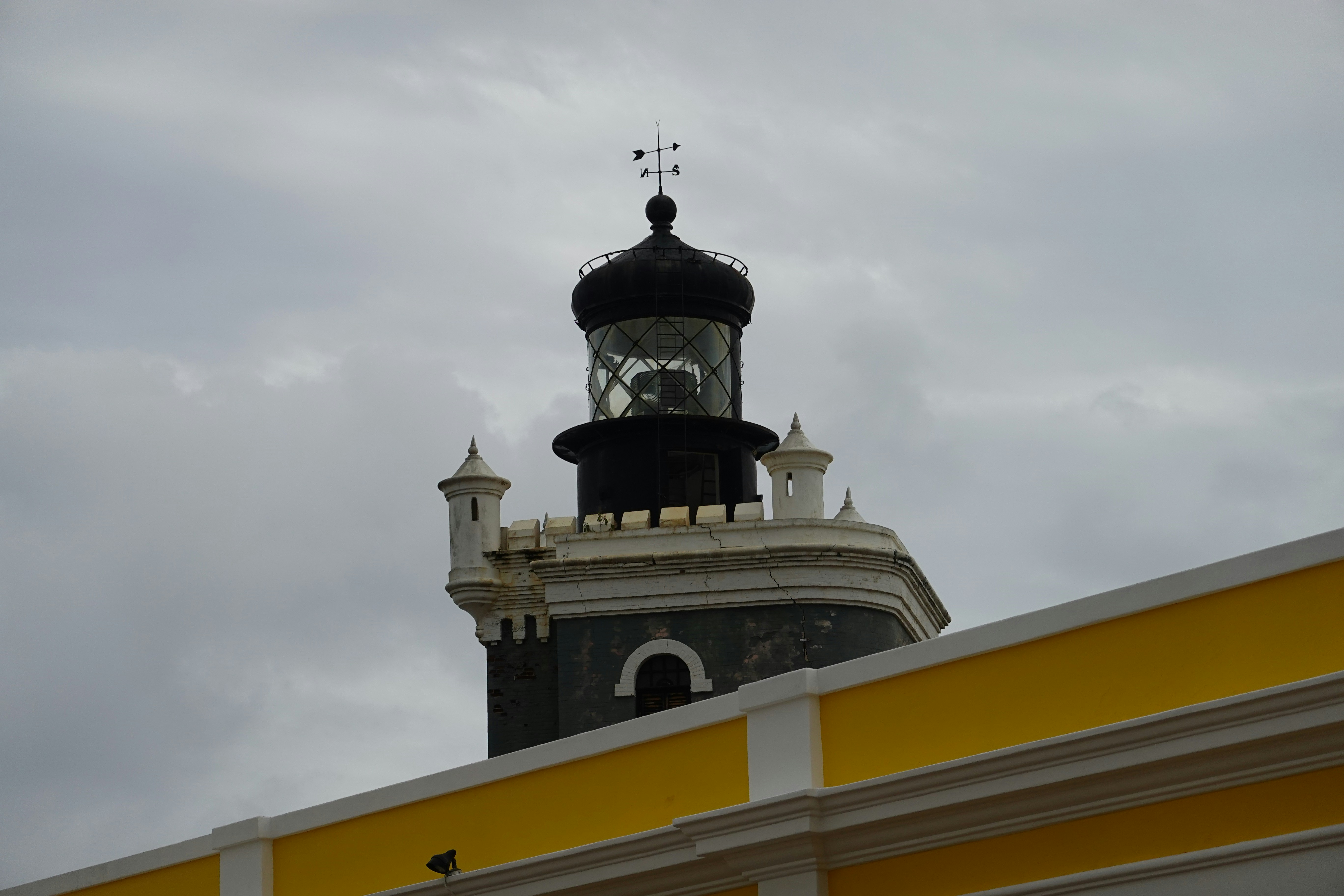 a black and white lighthouse on top of a yellow and white building