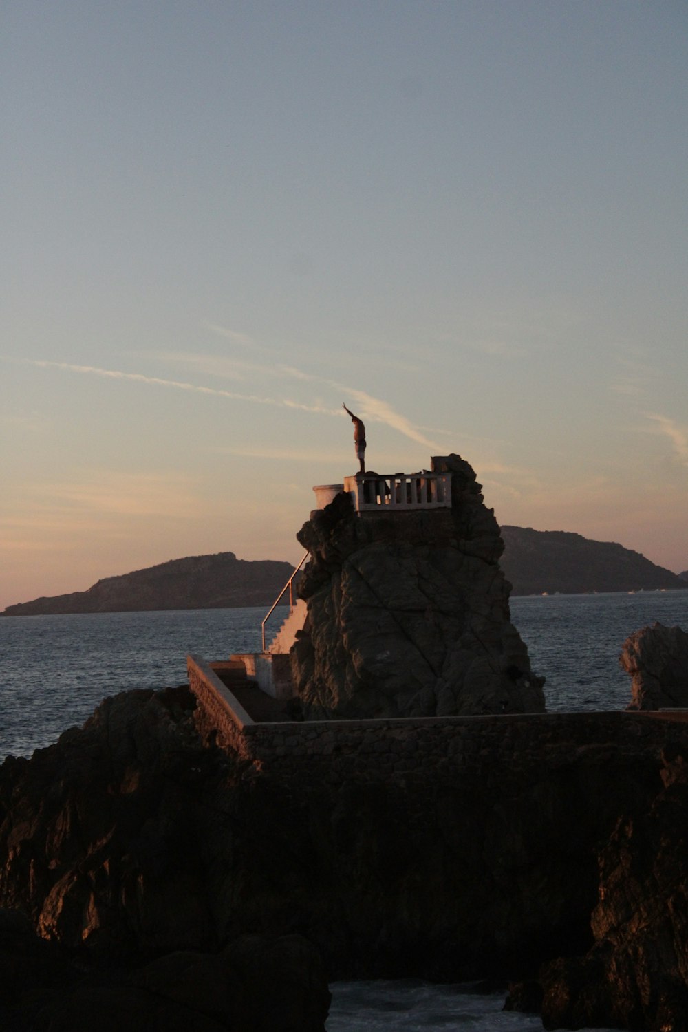 a person standing on top of a rock next to the ocean