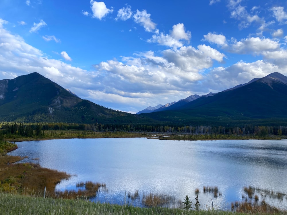 Un lac entouré de montagnes sous un ciel bleu nuageux