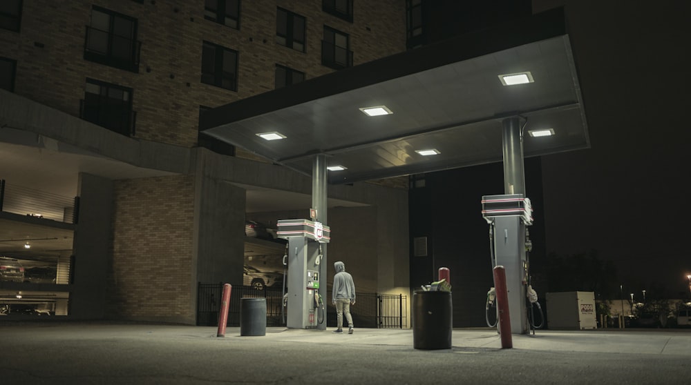 a gas station at night with people standing at the gas pumps