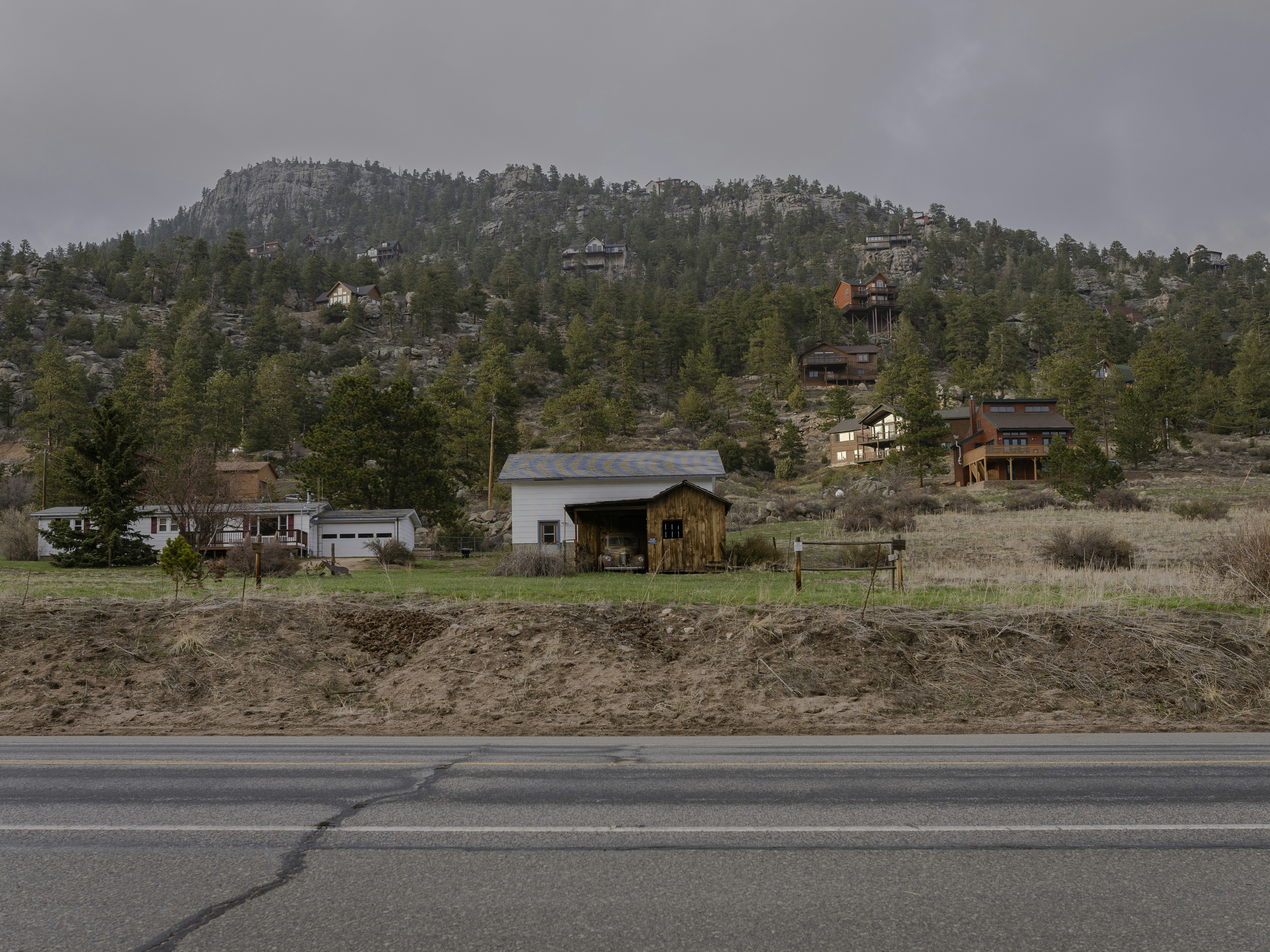 a house on the side of the road with a mountain in the background