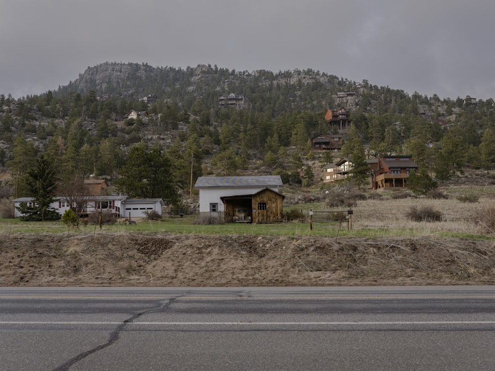 a house on the side of the road with a mountain in the background