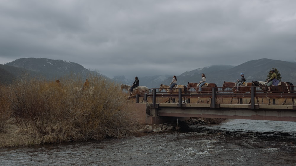 a group of people riding horses across a bridge