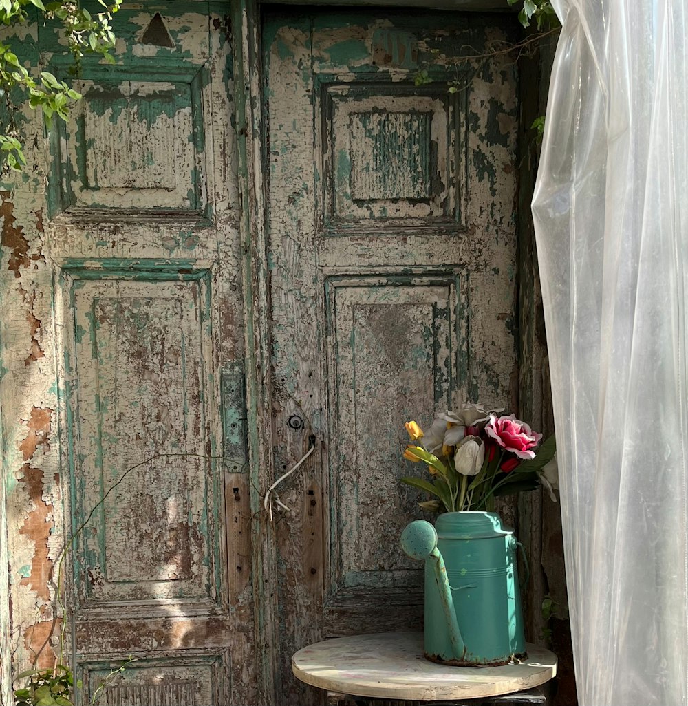 a vase of flowers sitting on a table in front of a door