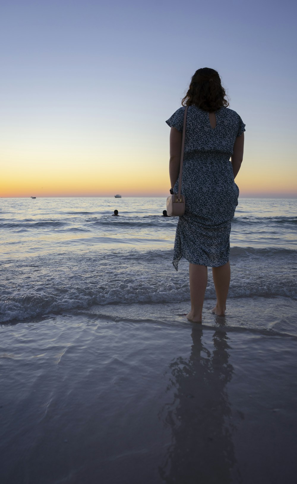 a woman standing on a beach at sunset