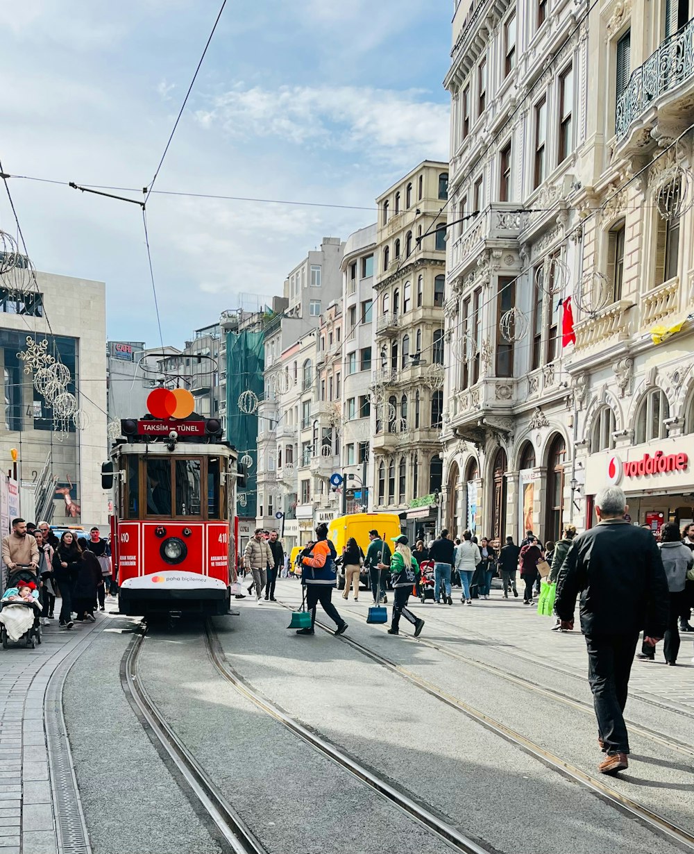 a red trolley car traveling down a street next to tall buildings