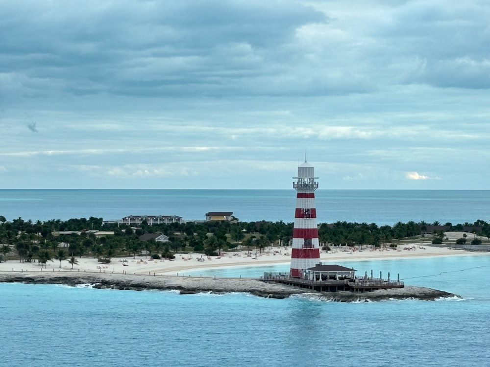 a red and white lighthouse on an island in the middle of the ocean