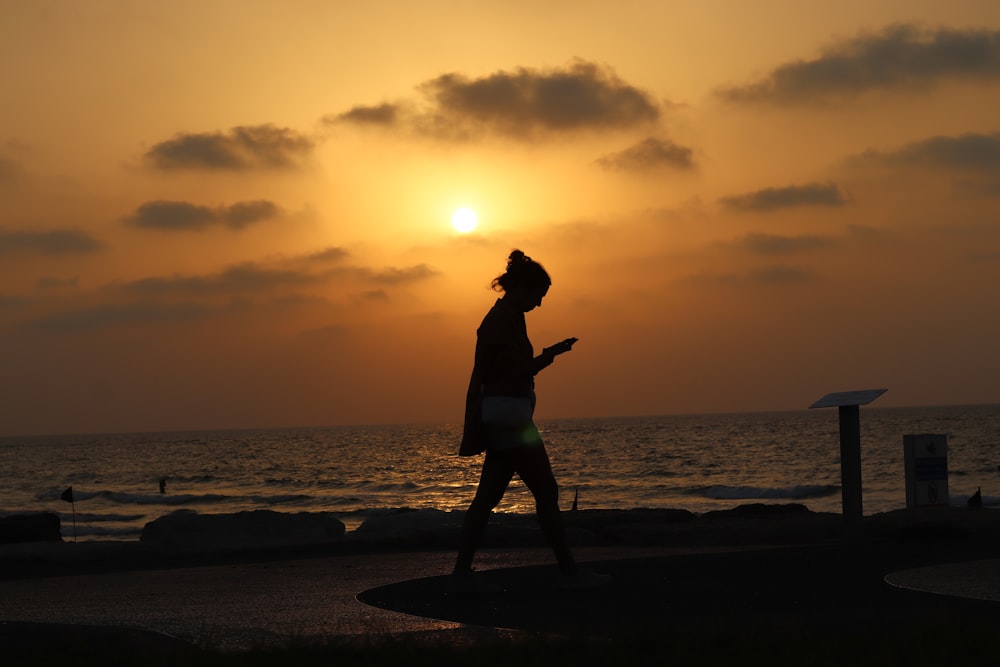 a person walking on the beach at sunset