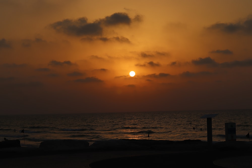 the sun is setting over the ocean on a cloudy day