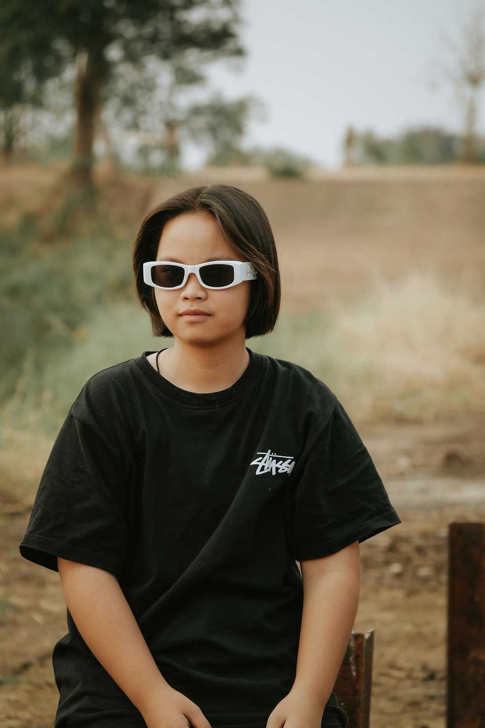 a girl wearing sunglasses sitting on a bench