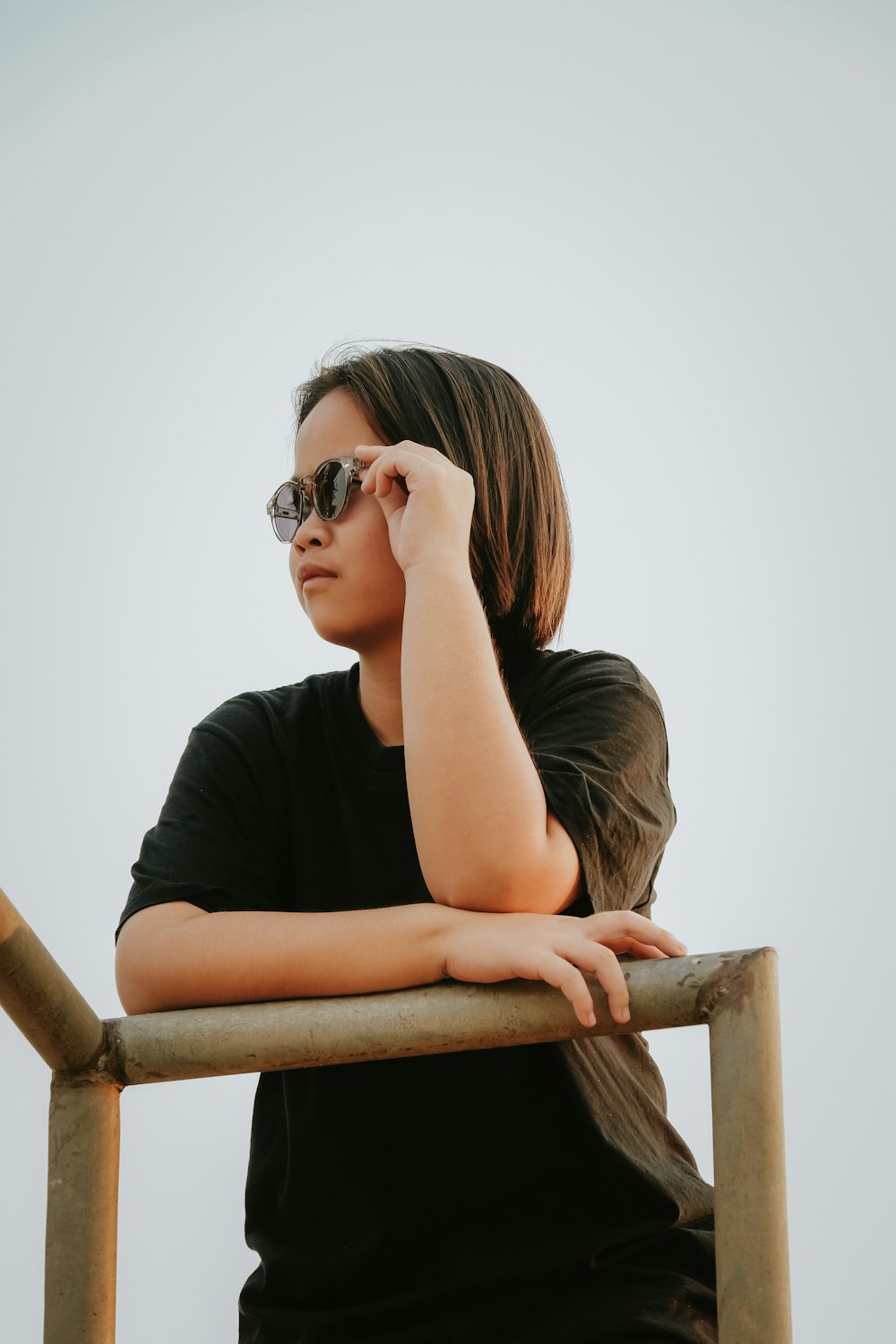 a woman wearing sunglasses leaning on a rail