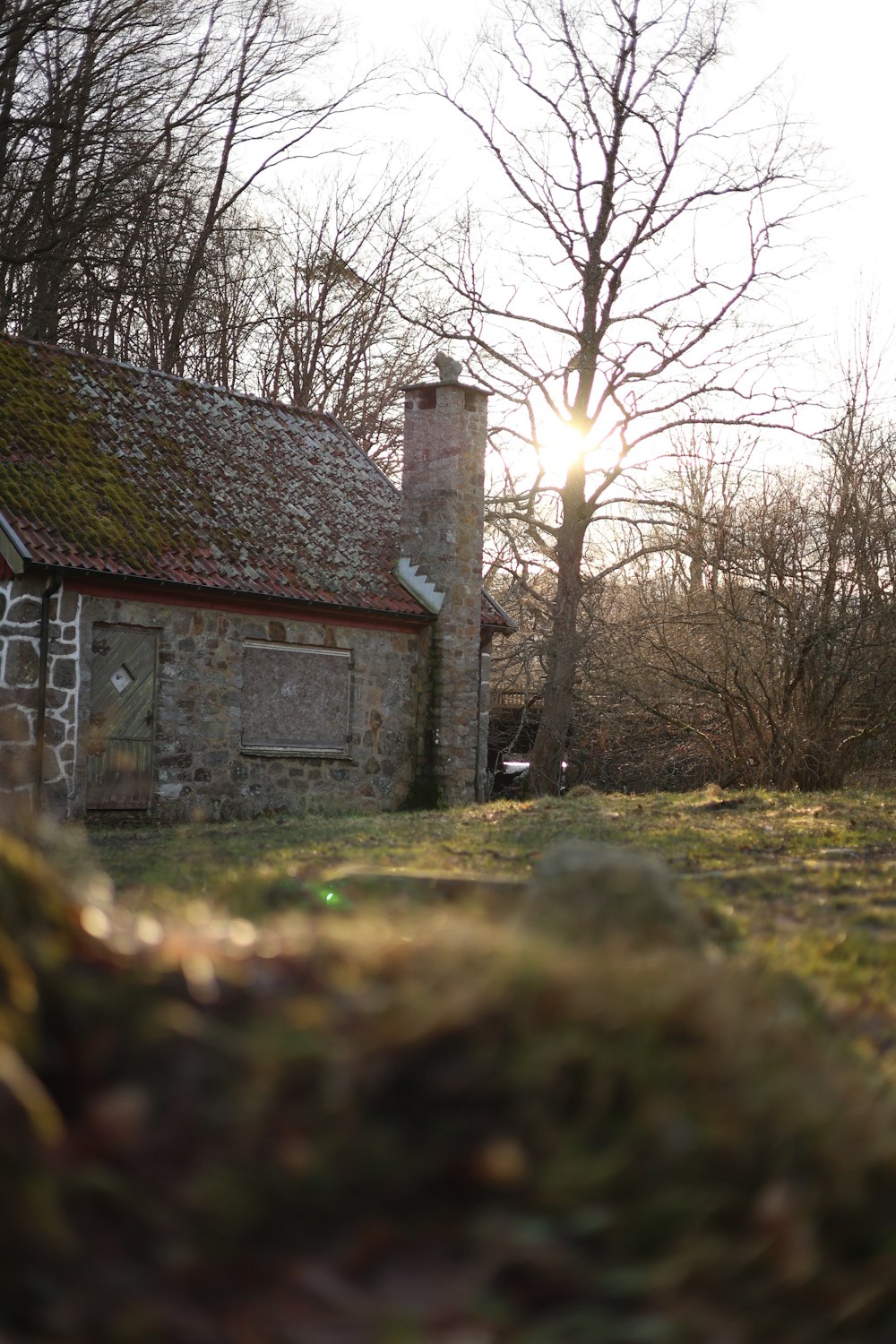 a stone house with a green roof and a brick chimney