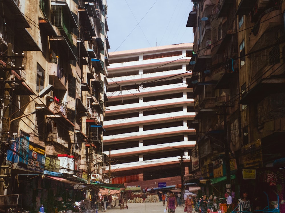 a group of people walking down a street next to tall buildings