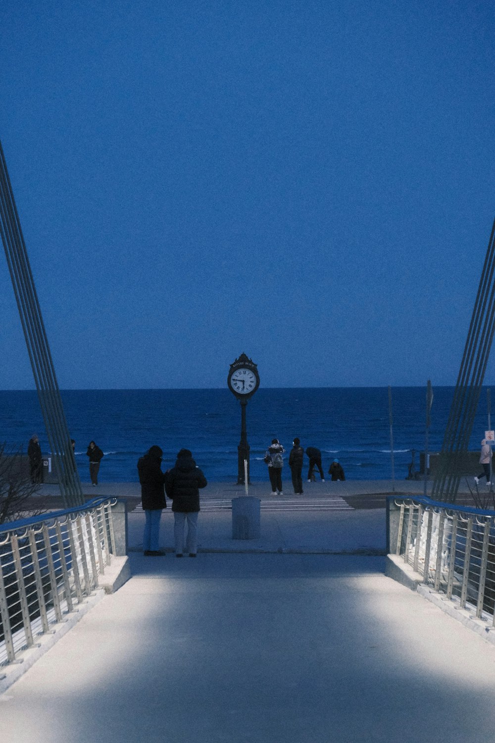 a group of people standing on a pier next to the ocean