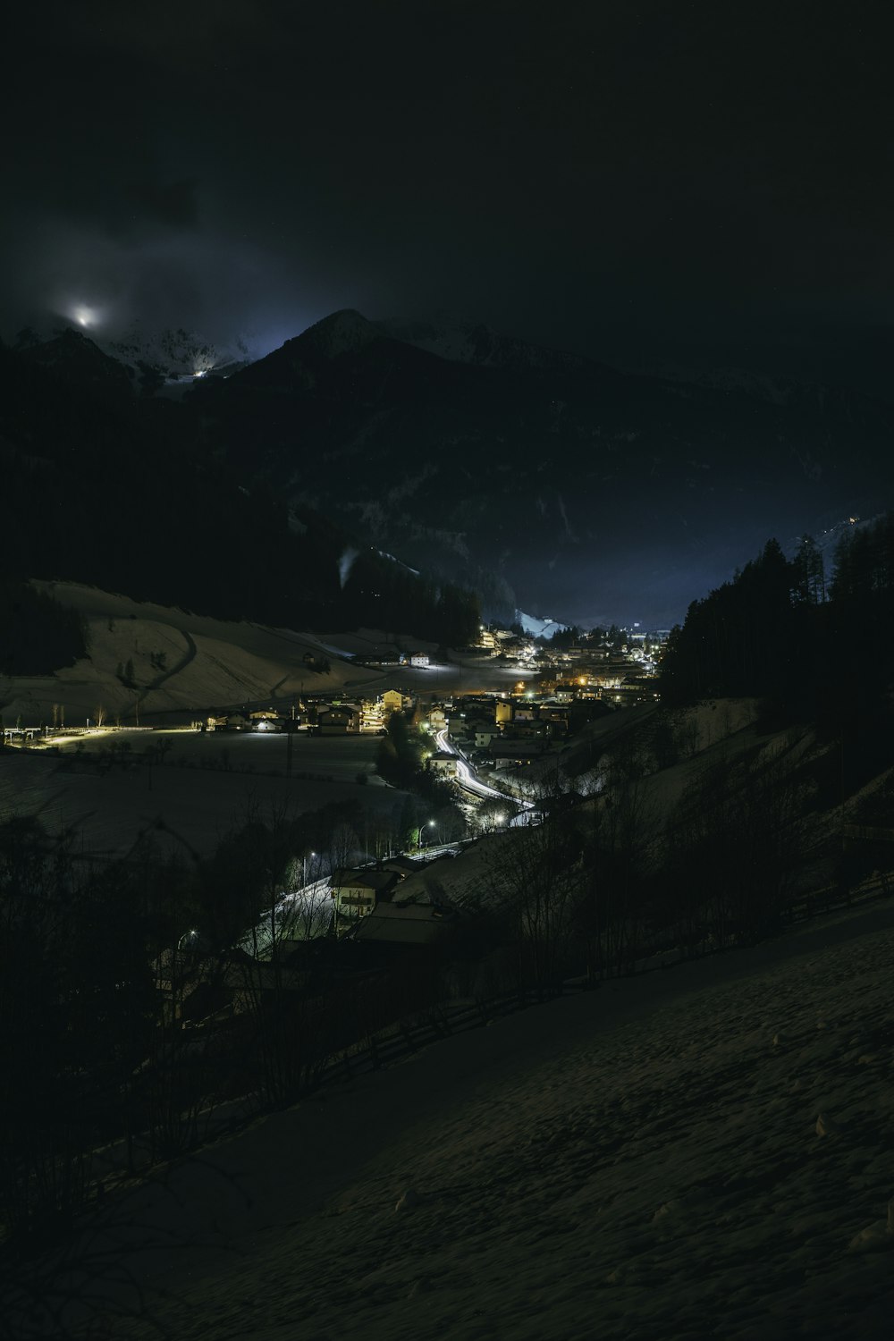 a night time view of a town with mountains in the background