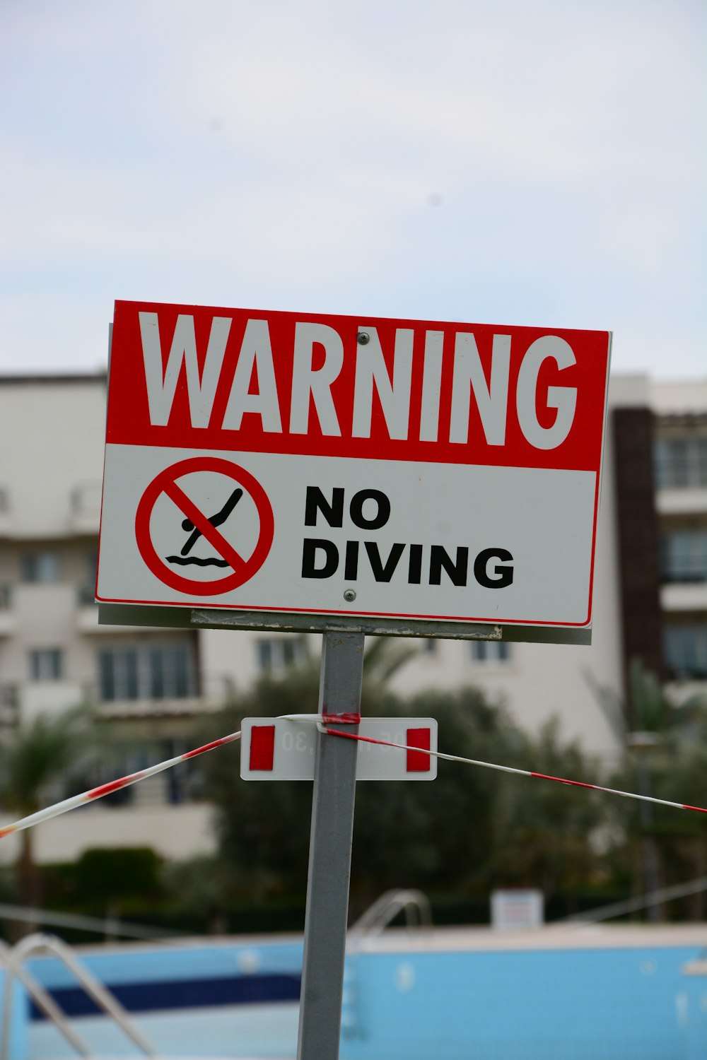 a red and white sign warning of no diving