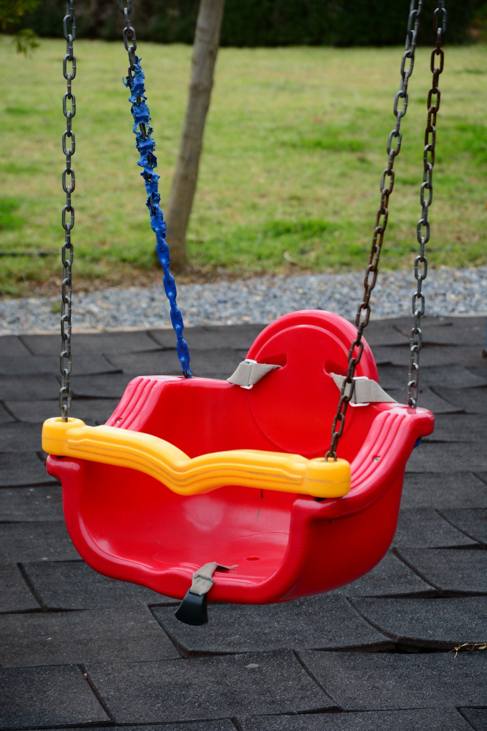 a red swing with a yellow seat on a brick patio