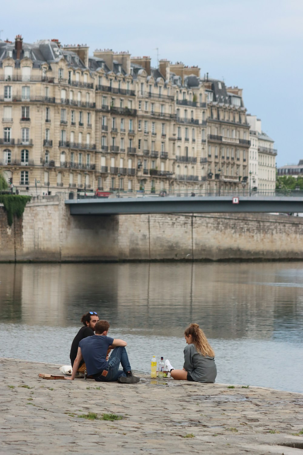 a couple of people sitting on the ground next to a body of water