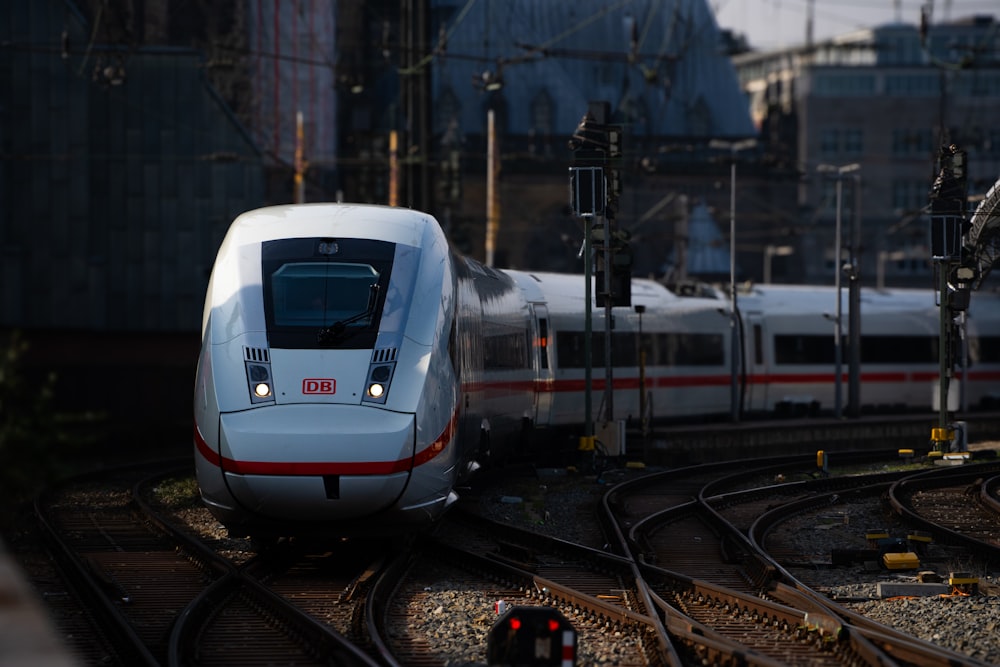 a white train traveling down train tracks next to a tall building