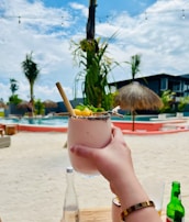 a person holding a drink on a beach