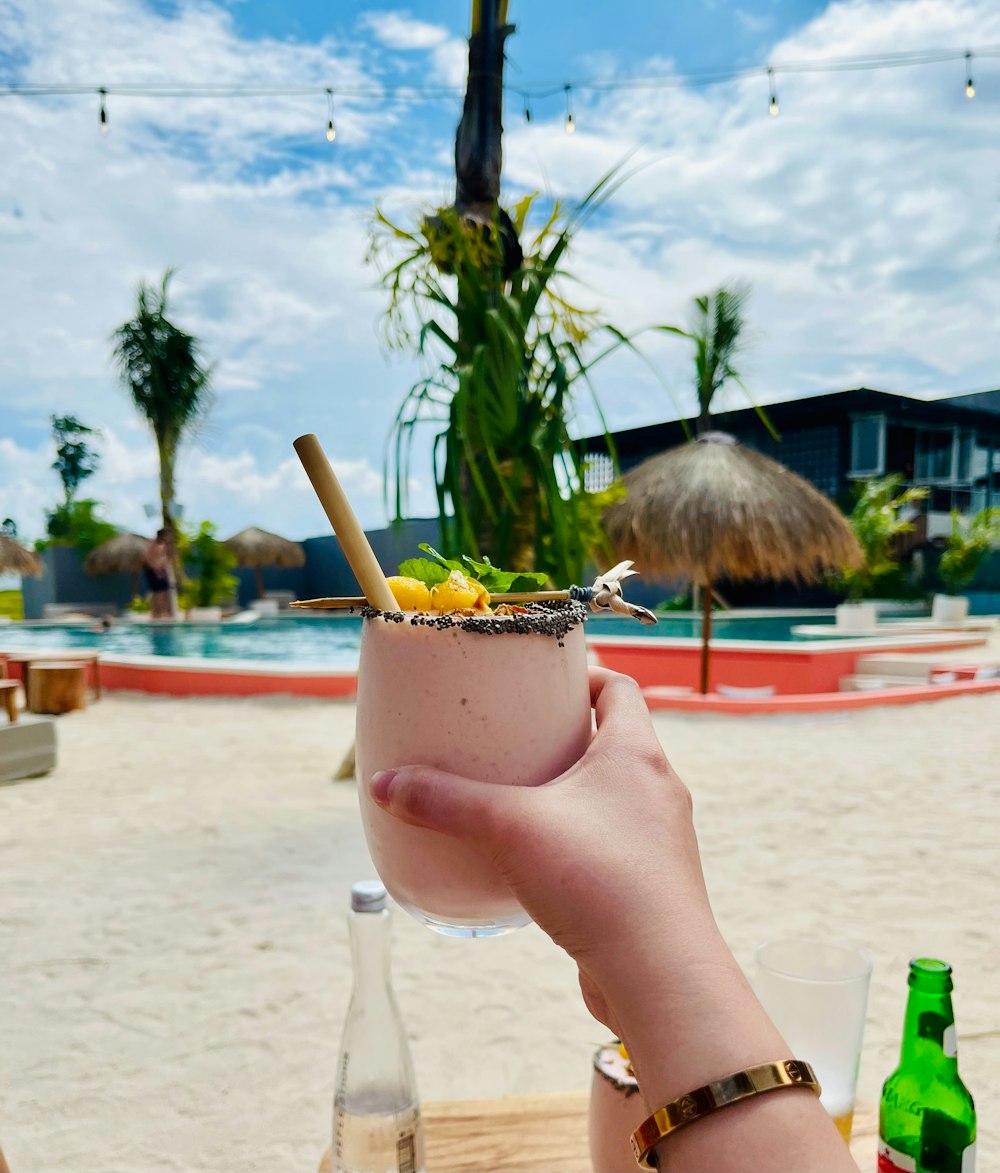 a person holding a drink on a beach