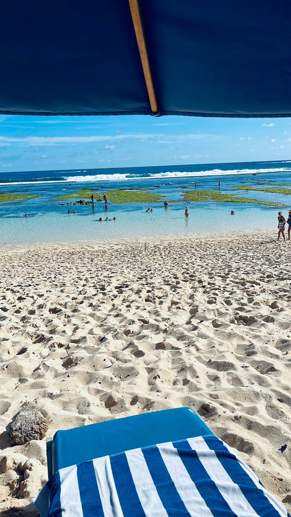 uma toalha de praia listrada azul e branca sentada em cima de uma praia de areia