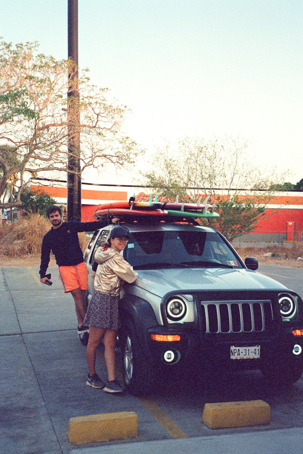 a man and a woman standing next to a parked jeep