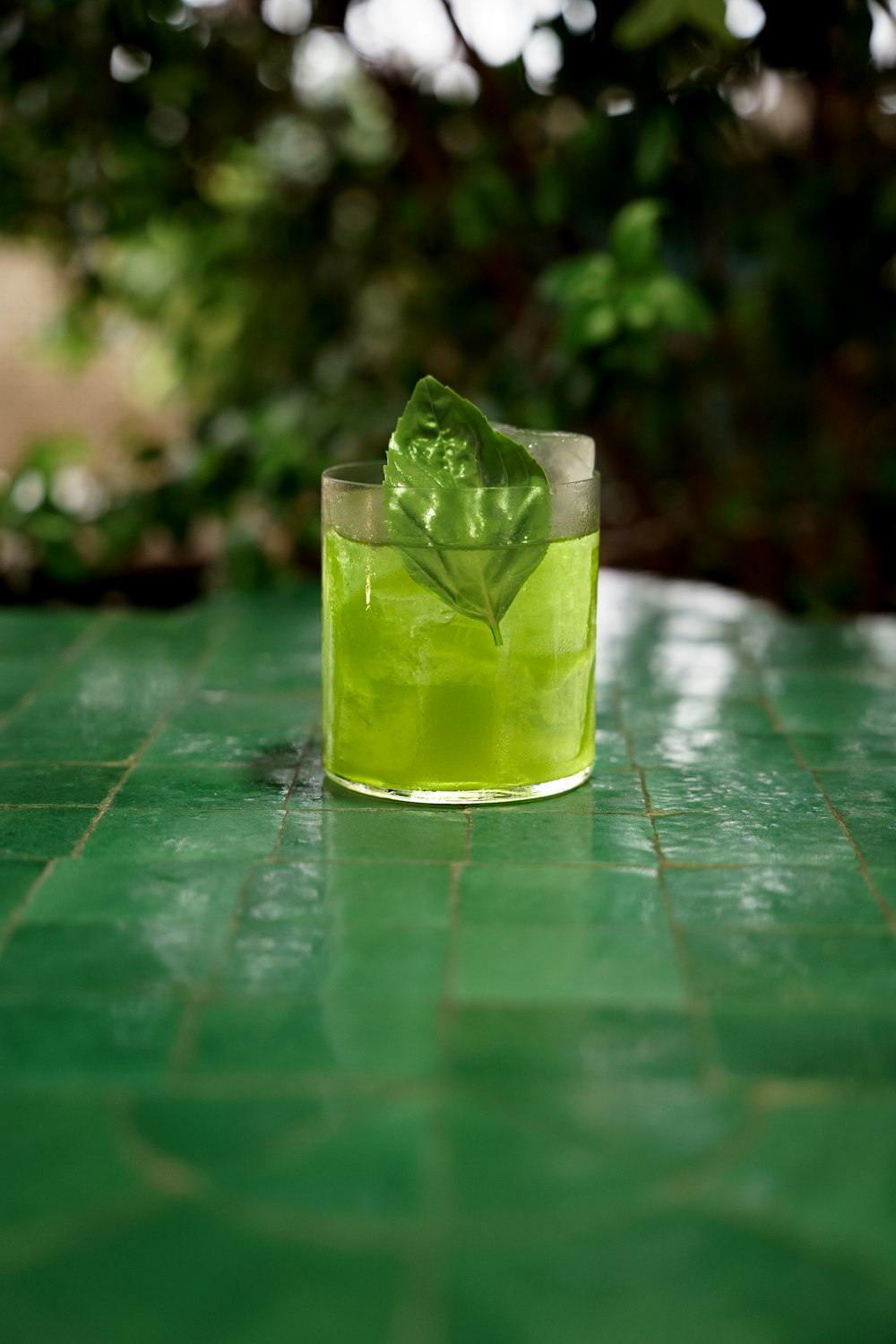 a glass of green liquid sitting on top of a green table