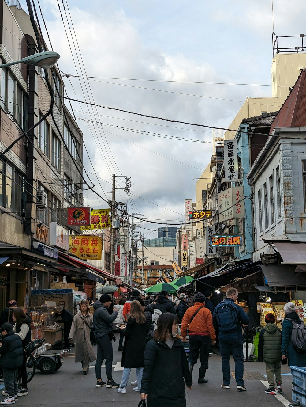 a crowd of people walking down a street next to tall buildings