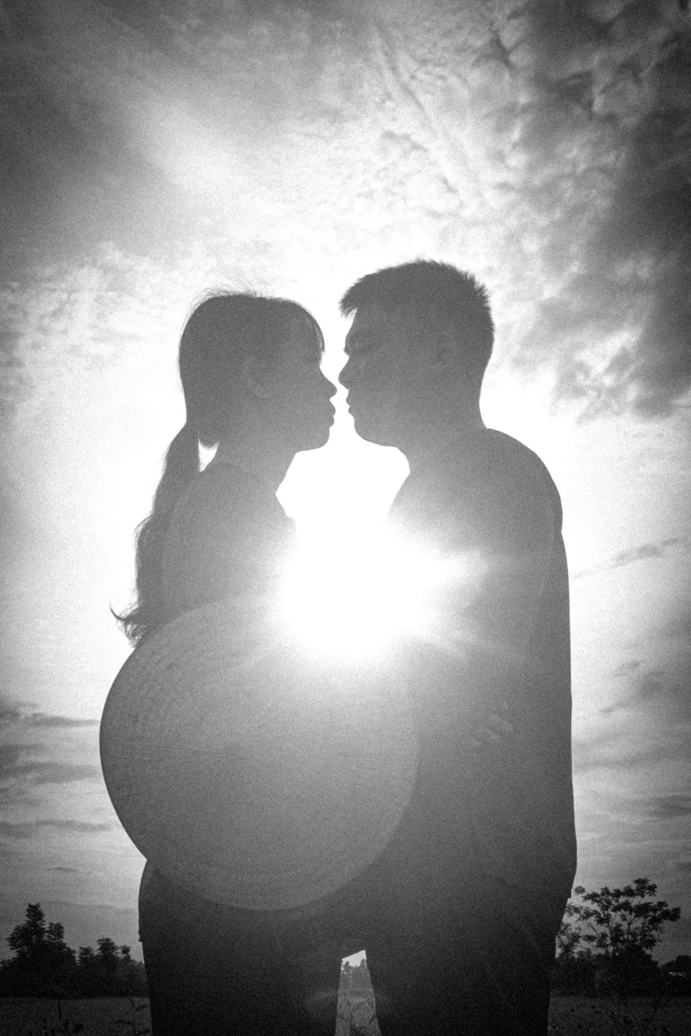 a black and white photo of a couple kissing
