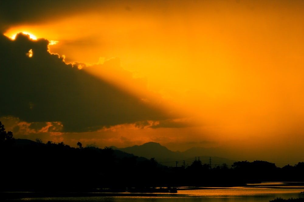 the sun is shining through the clouds over a body of water