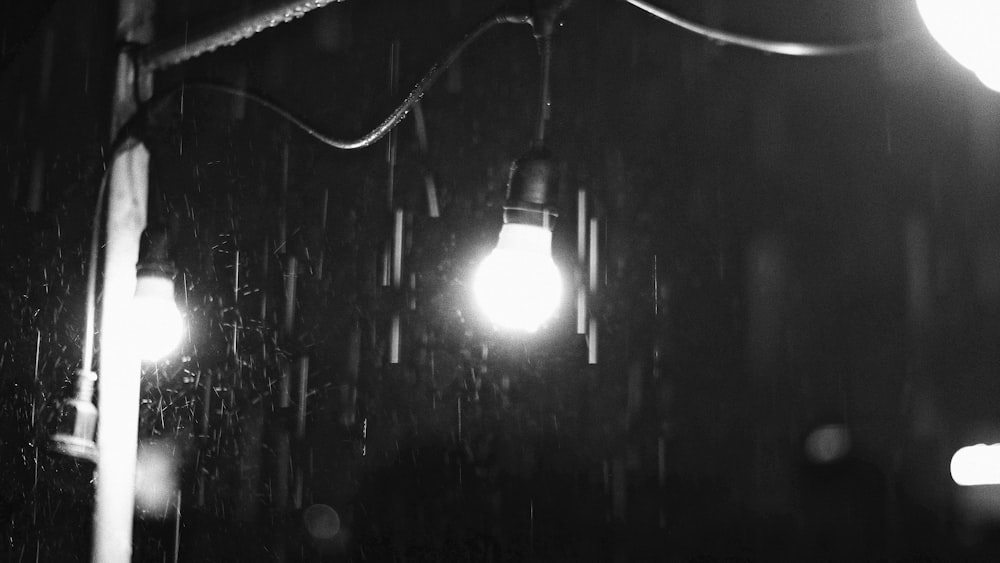 a black and white photo of a street light in the rain