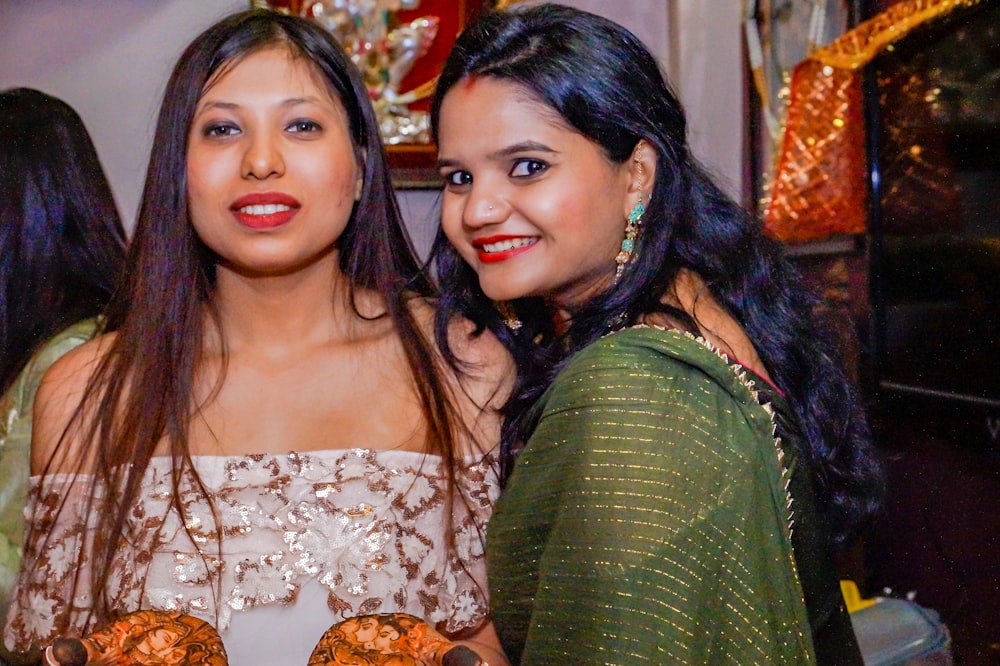 two women standing next to each other holding donuts