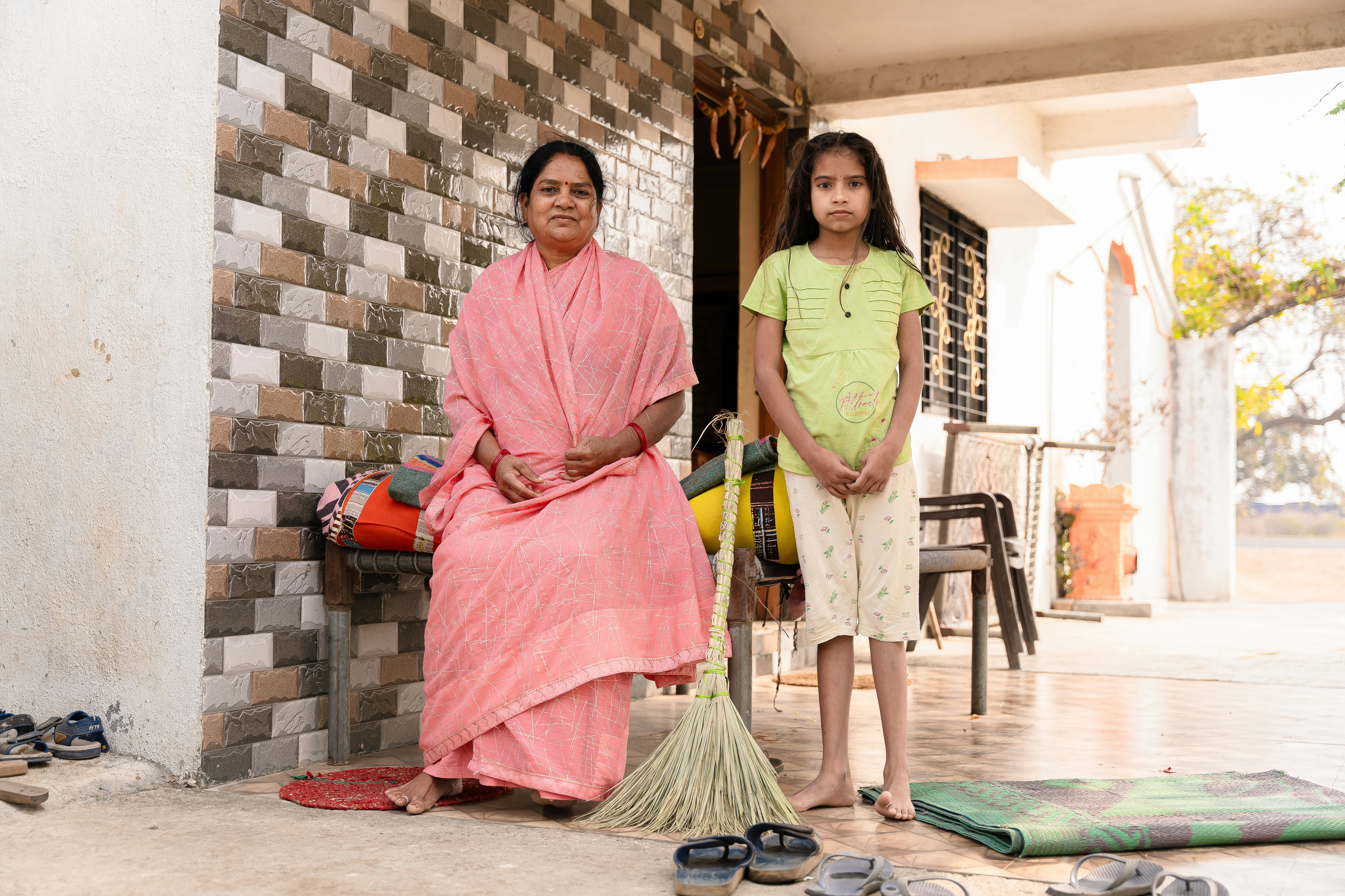 a woman and a girl are standing outside a house